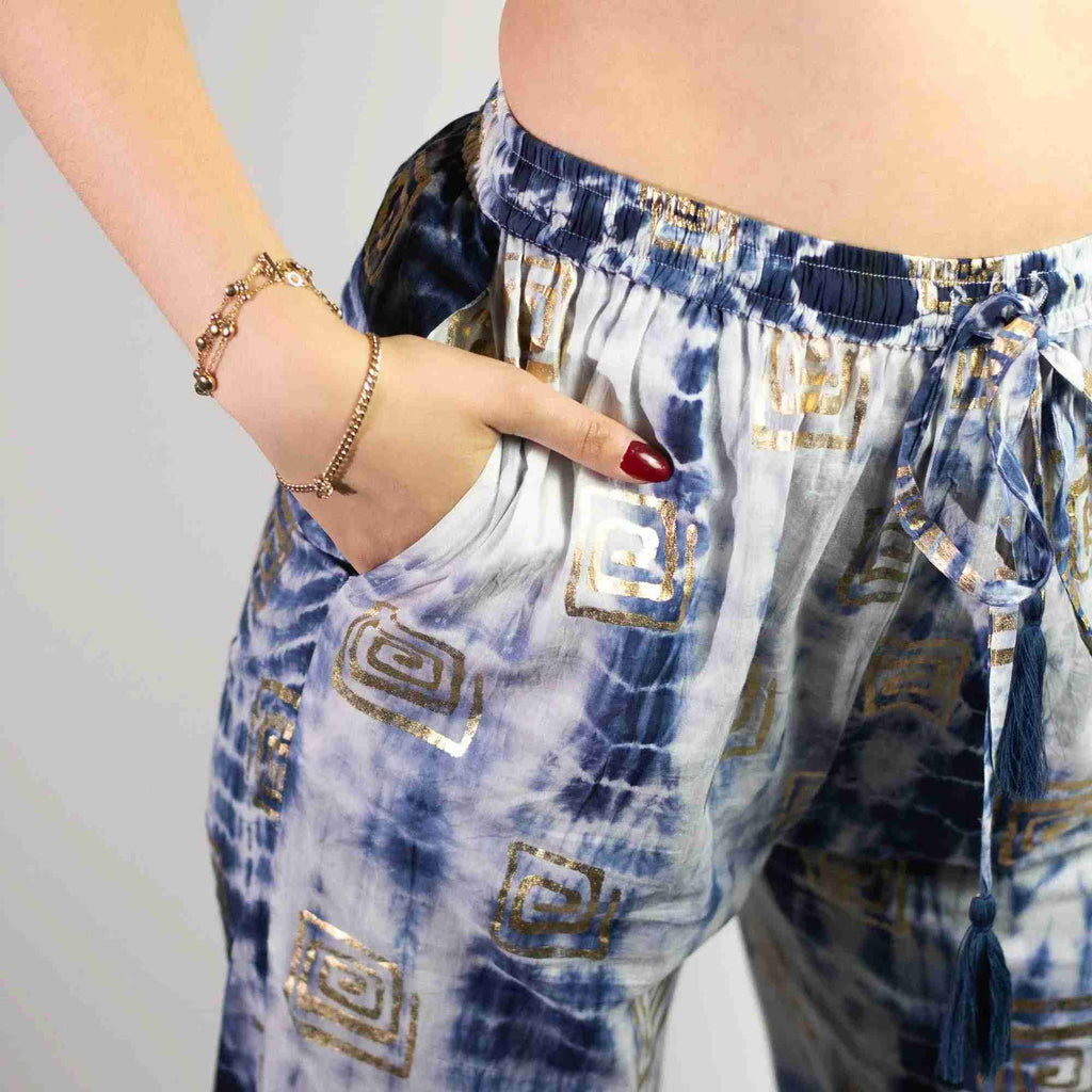 Pantalon bleu clair à motif grec doré, taille élastique et liens à pompons.