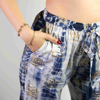 Pantalon bleu clair à motif grec doré, taille élastique et liens à pompons.