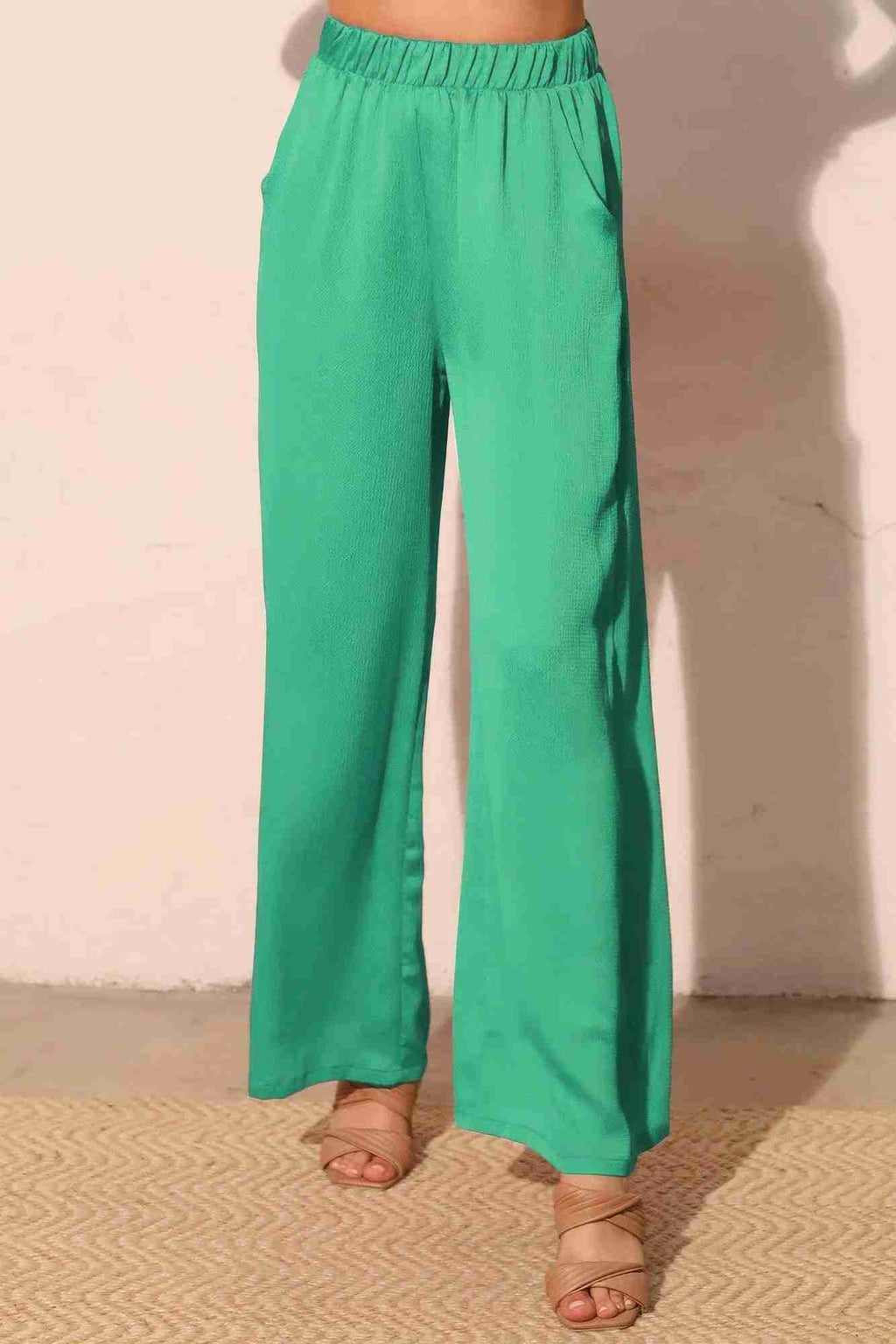 Pantalon satiné fluide vert émeraude, taille élastique, jambes larges, poches latérales.