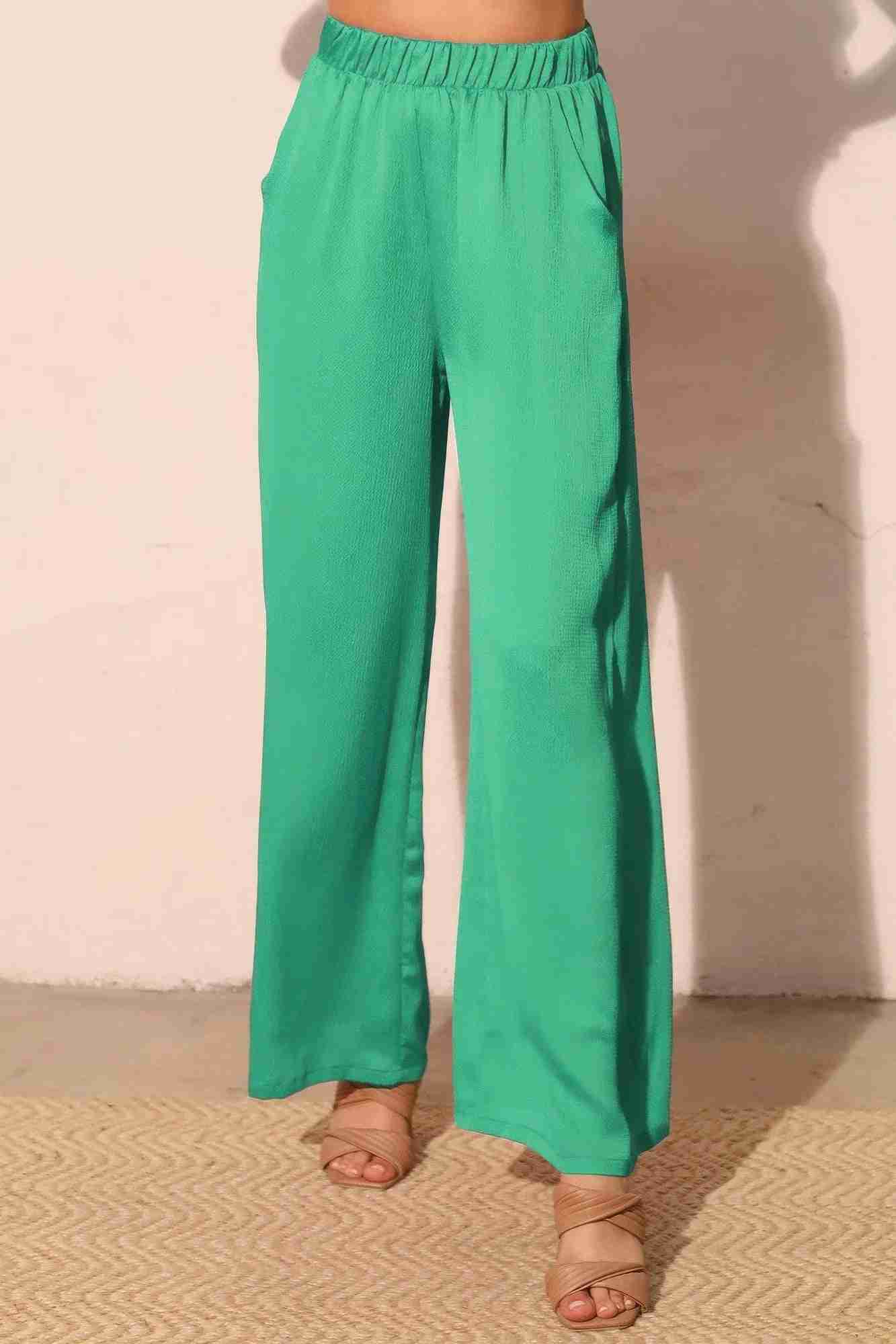 Pantalon satiné fluide vert émeraude, taille élastique, jambes larges, poches latérales.