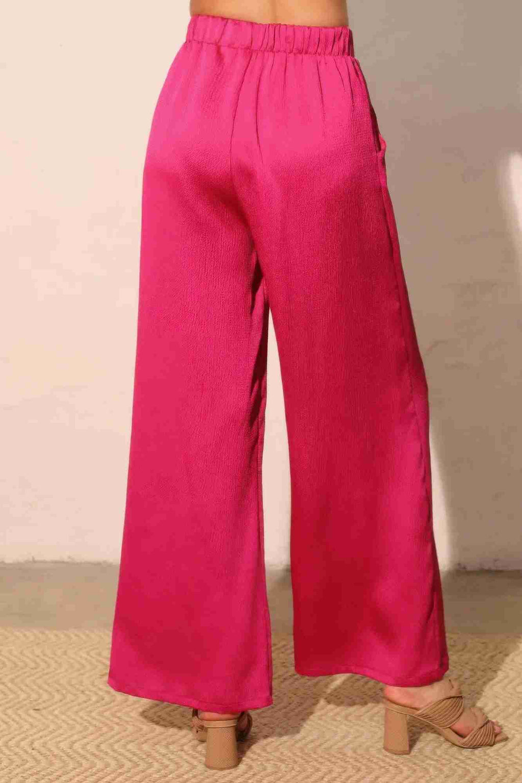 Pantalon satiné fluide fuchsia, vue de profil, taille élastique, jambes amples.