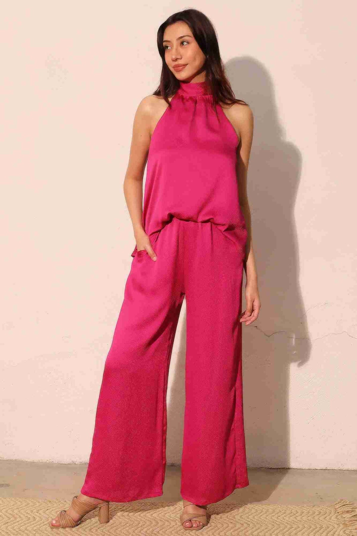Pantalon satiné fluide fuchsia, taille élastique haute, jambe ample, poches visibles.