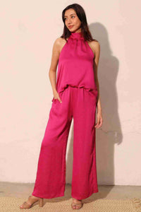 Pantalon satiné fluide fuchsia, taille élastique haute, jambe ample, poches visibles.