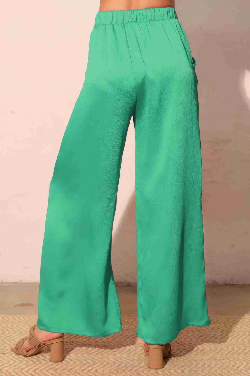 Pantalon satiné fluide vert émeraude, vue de dos, taille élastique, jambe ample.