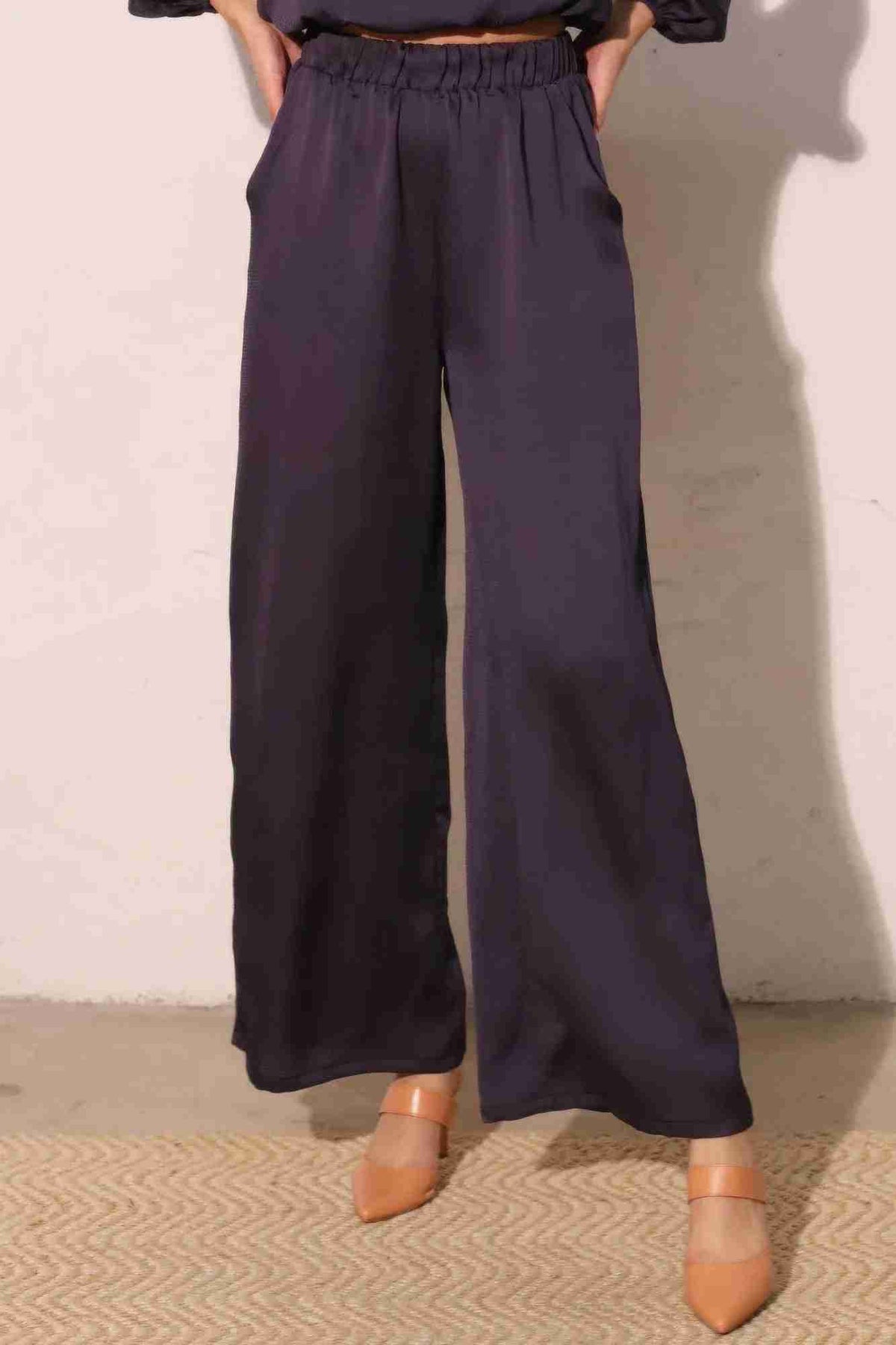 Pantalon satiné fluide marine foncé, taille élastique, jambes larges, poches latérales.