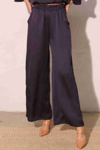 Pantalon satiné fluide marine foncé, taille élastique, jambes larges, poches latérales.