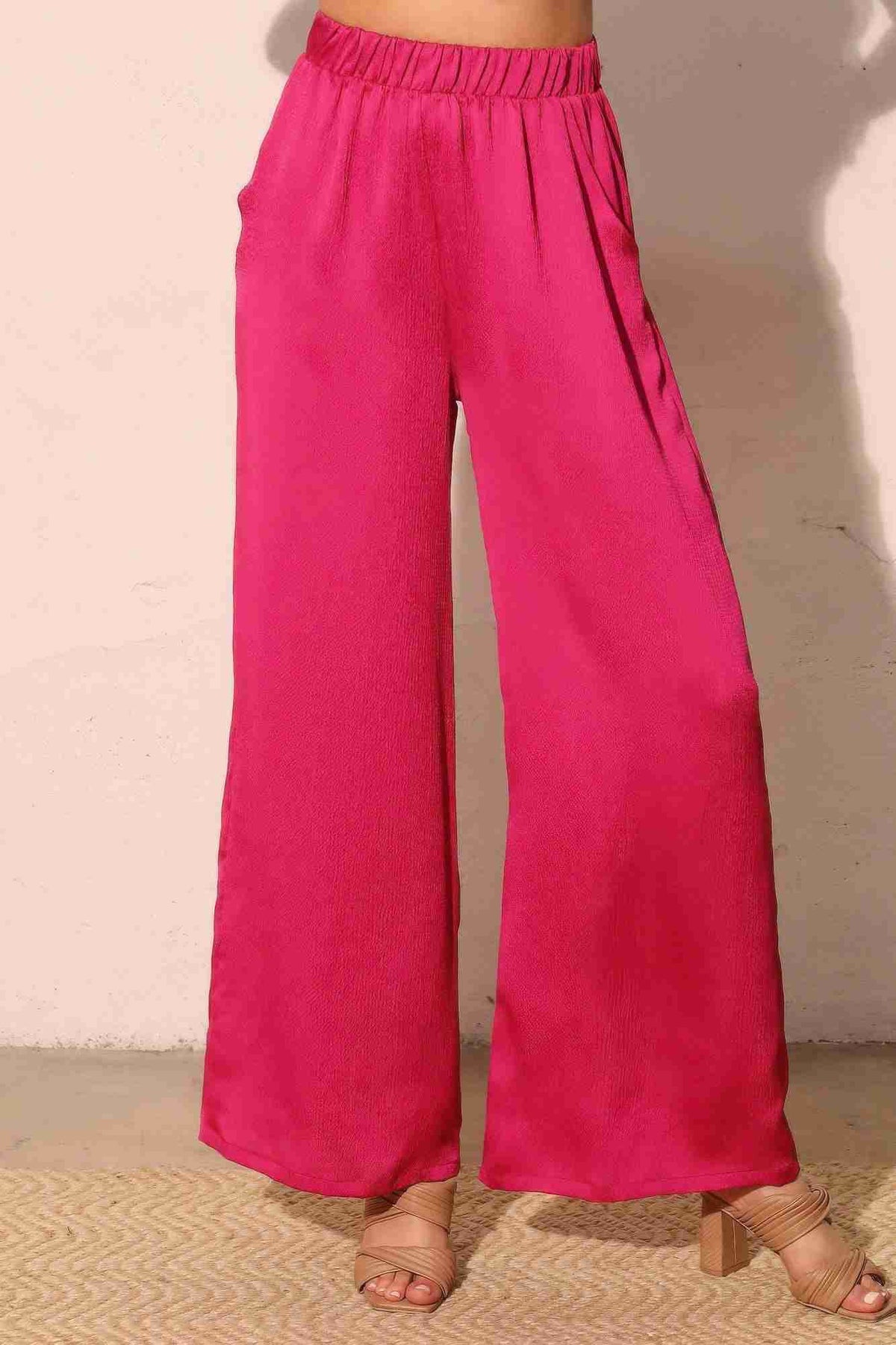 Pantalon satiné fluide fuchsia, taille élastique, jambes larges, poches latérales.