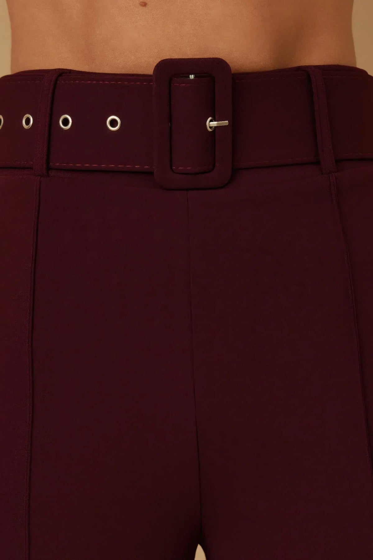 Détail pantalon bordeaux : ceinture à boucle carrée et œillets sur le passants