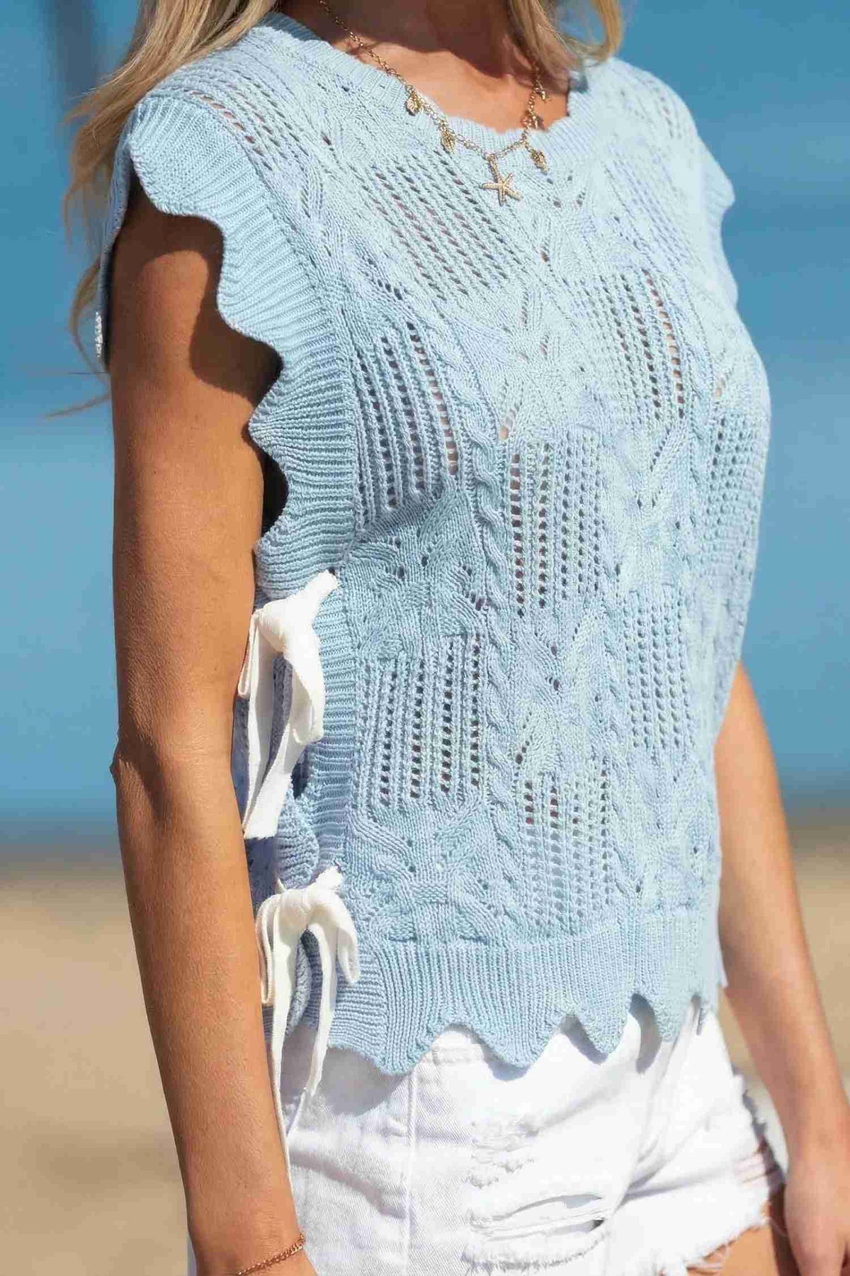 Pull en tricot pointelle vert menthe, manches courtes, détails ajourés et bord festonné