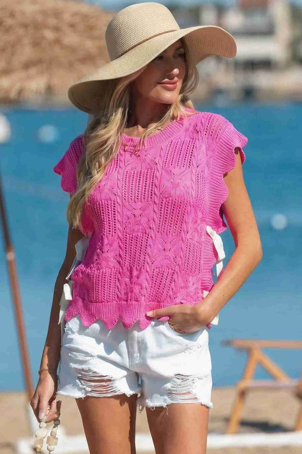 Pull femme en tricot pointelle rose vif, manches courtes et bord festonné