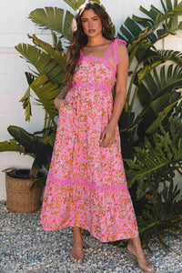 Robe longue rose à motif floral, bretelles volants et ourlet à volants.