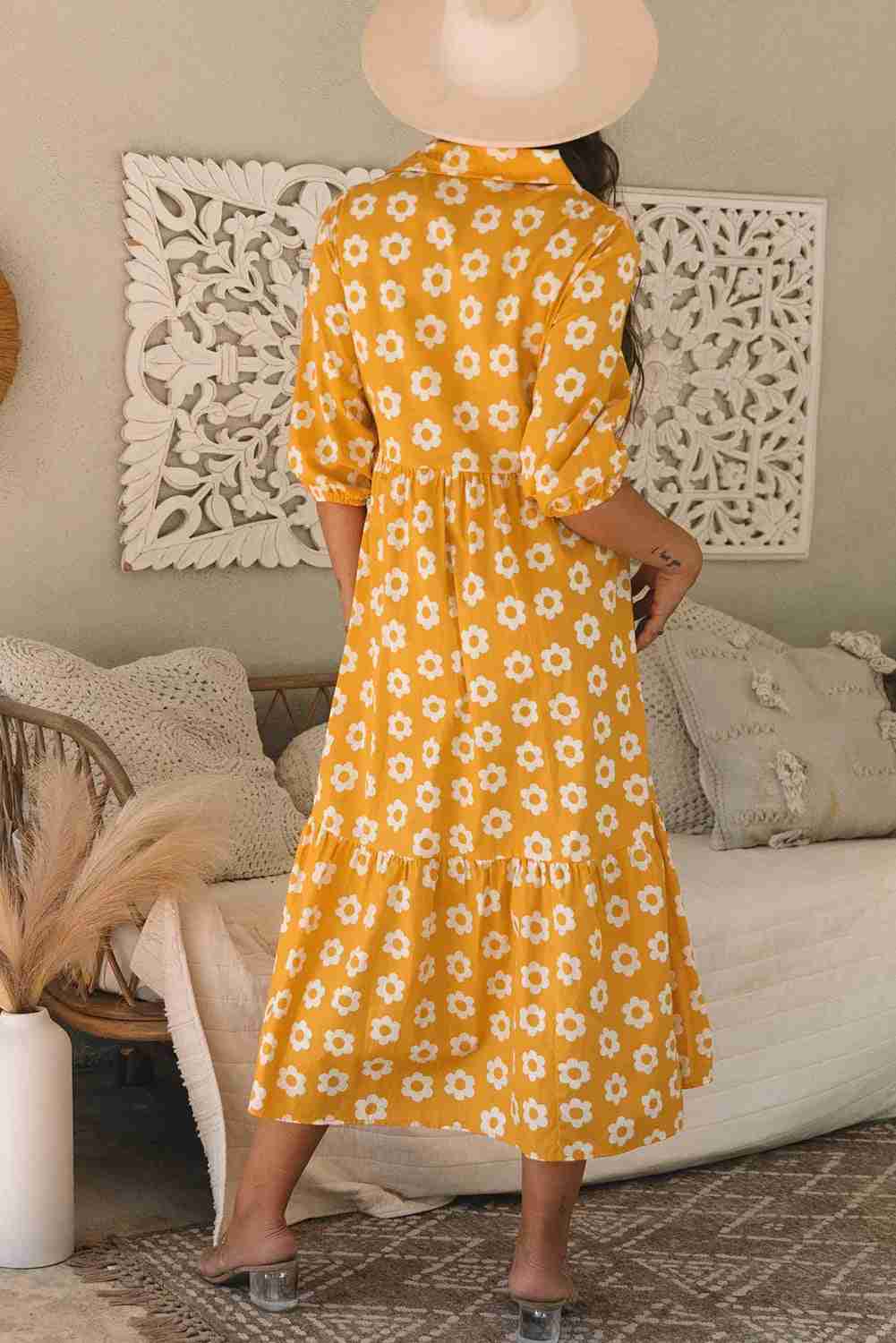 Robe maxi jaune à fleurs blanches, manches évasées, encolure boutonnée au dos.