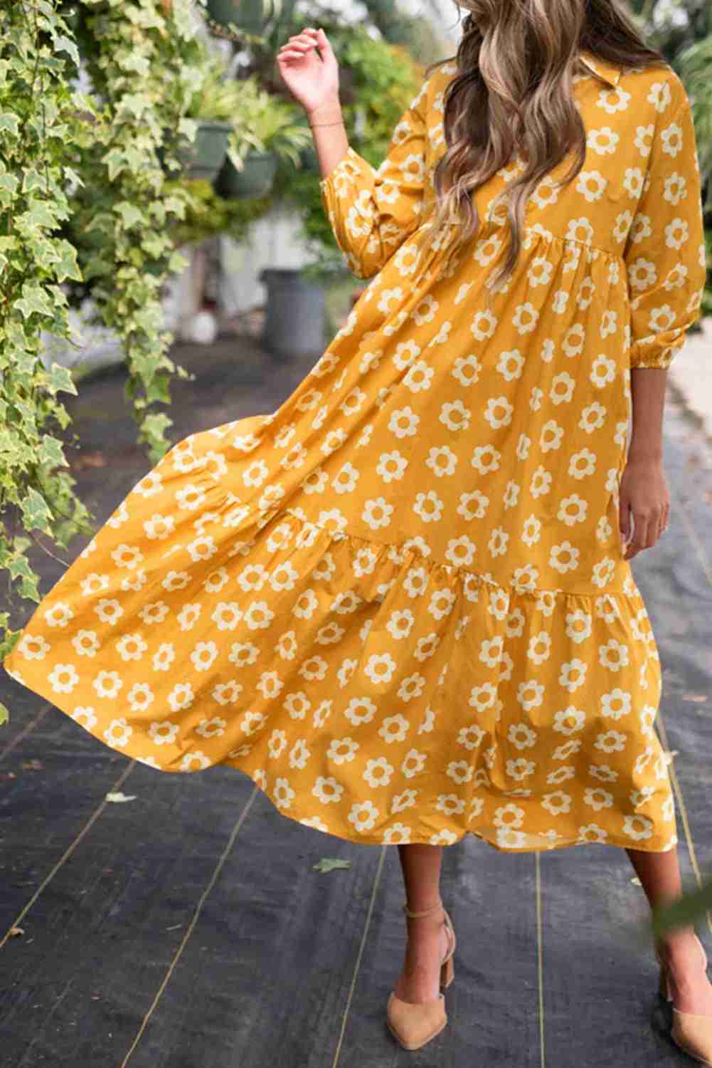 Robe maxi jaune à fleurs blanches, jupe ample et évasée, manches trois-quarts.