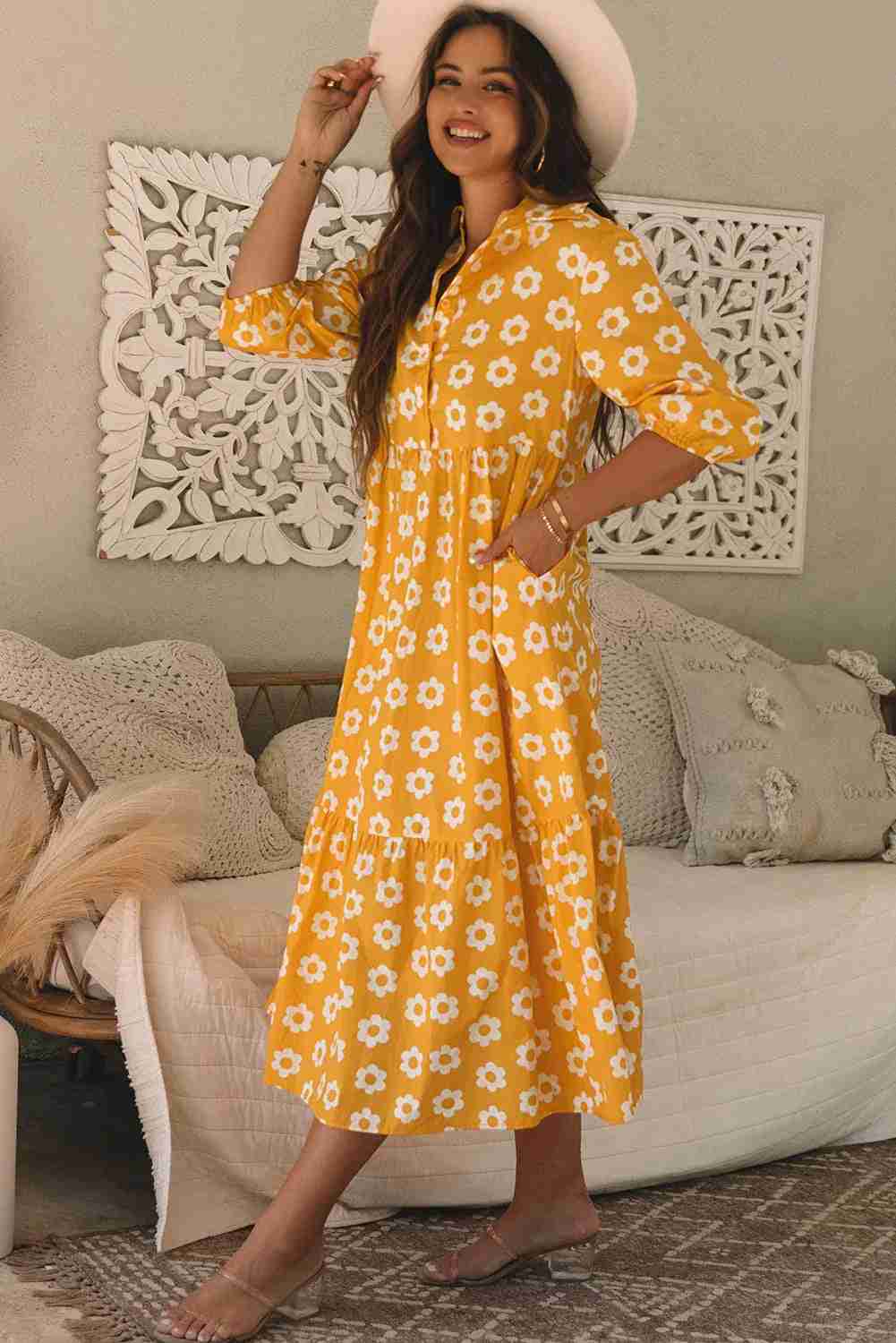 Robe maxi jaune à fleurs blanches, col chemisier, manches trois-quarts, boutons visibles.