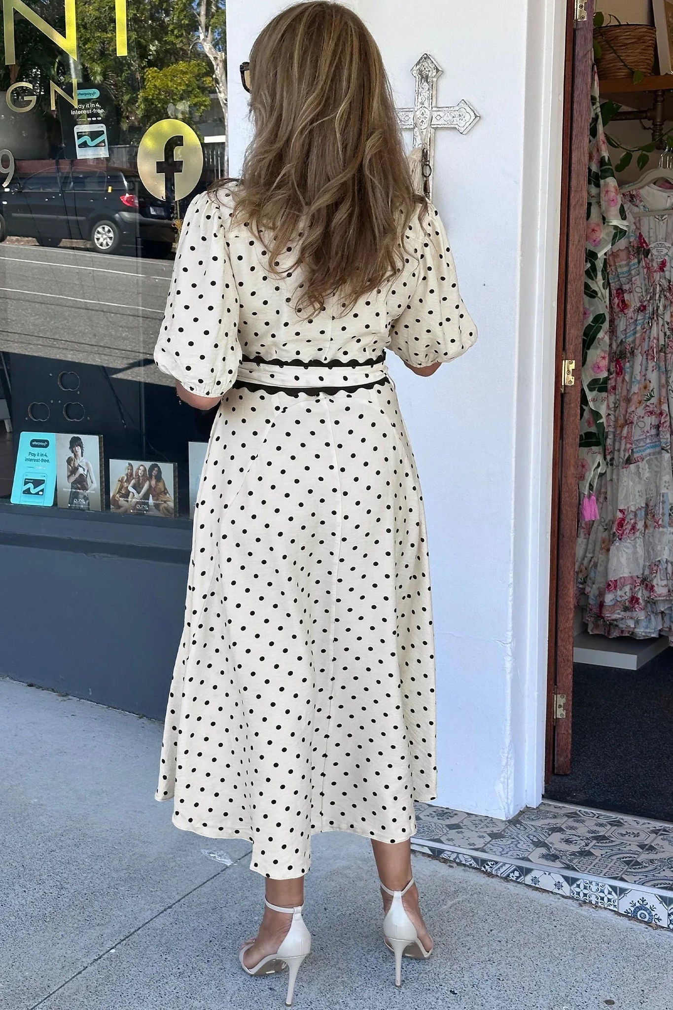Robe midi blanche à pois noirs vue de dos, ceinture nouée et manches trois-quarts.
