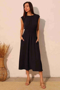 Robe midi noire sans manches à taille élastique, fronces et poches latérales.