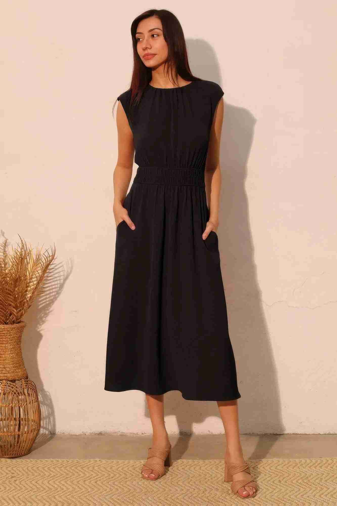 Robe midi noire sans manches à taille élastique, fronces et poches latérales.