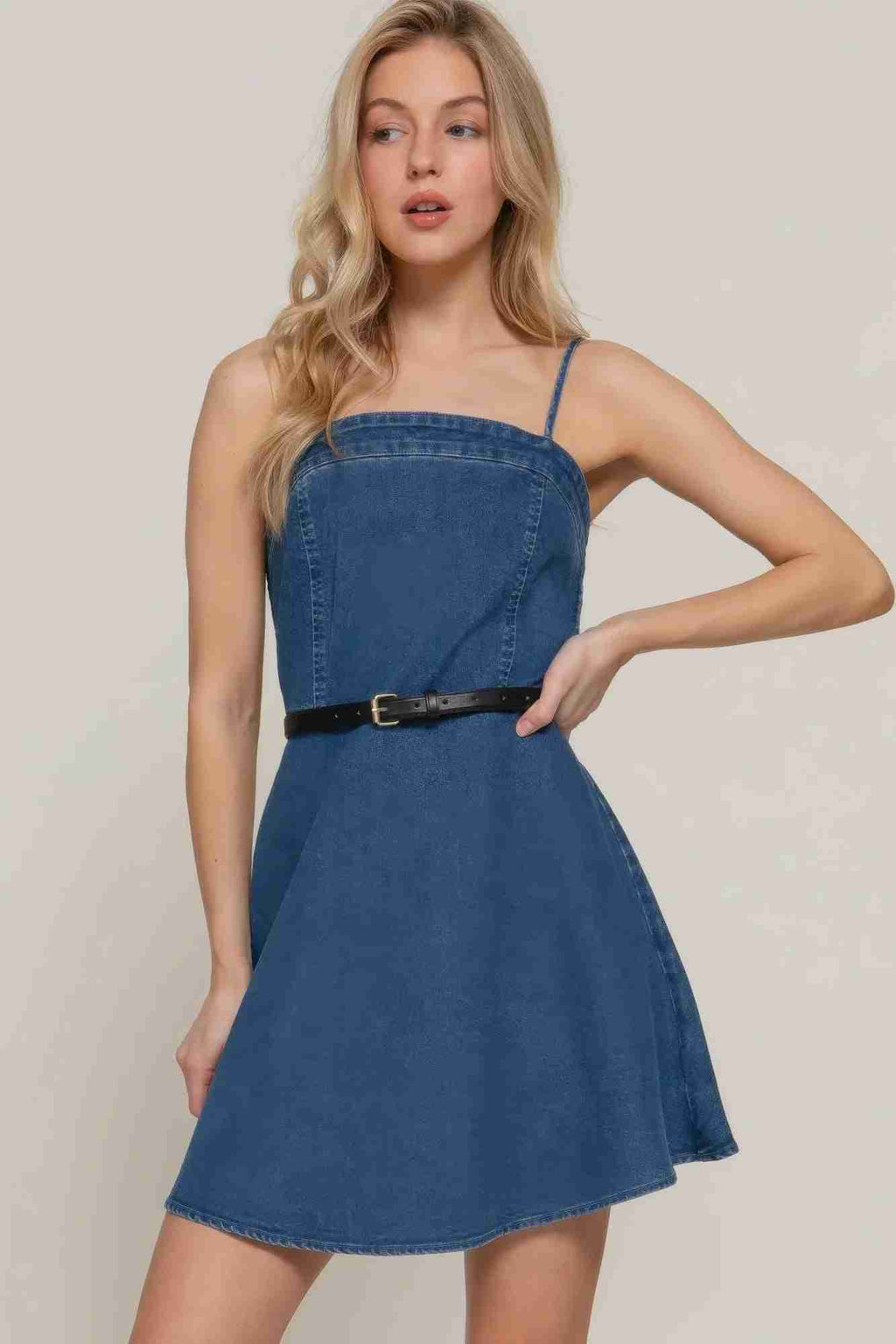 Robe mini en jean bleu foncé, bretelles fines, ceinture à boucle, coupe trapèze.