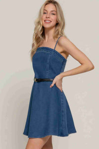 Robe mini en denim bleu foncé, bretelles fines, ceinture à boucle, encolure carrée.
