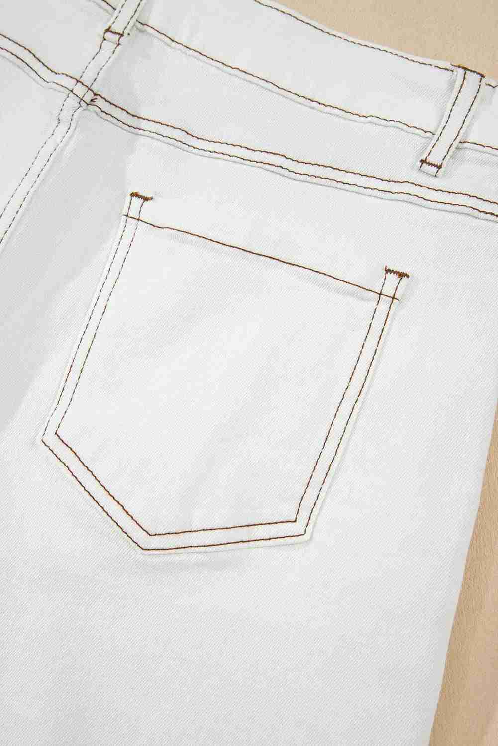 Poche avant et surpiqûres d’un short en jean blanc taille haute, ourlet effiloché.