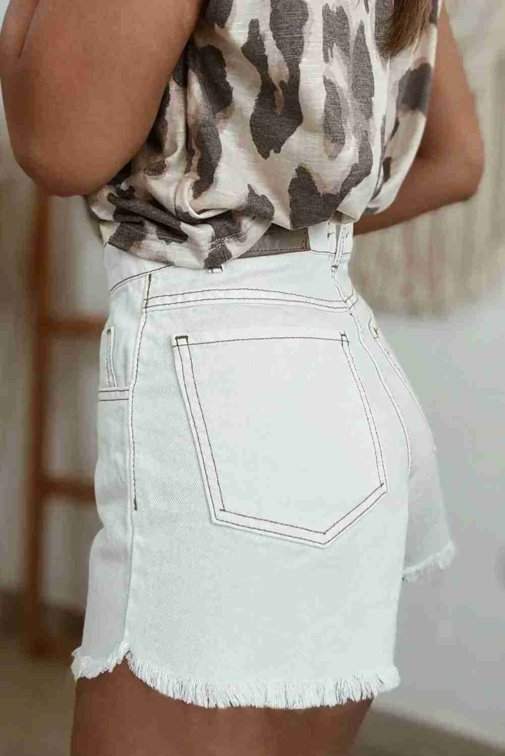 Short en jean blanc taille haute, poches avant cousues, ourlet effiloché et bouton.