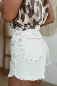 Short en jean blanc taille haute, poches avant cousues, ourlet effiloché et bouton.