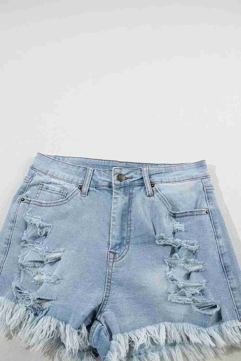 Short en jean bleu clair taille haute, déchirures devant, ourlet effiloché et poches visibles