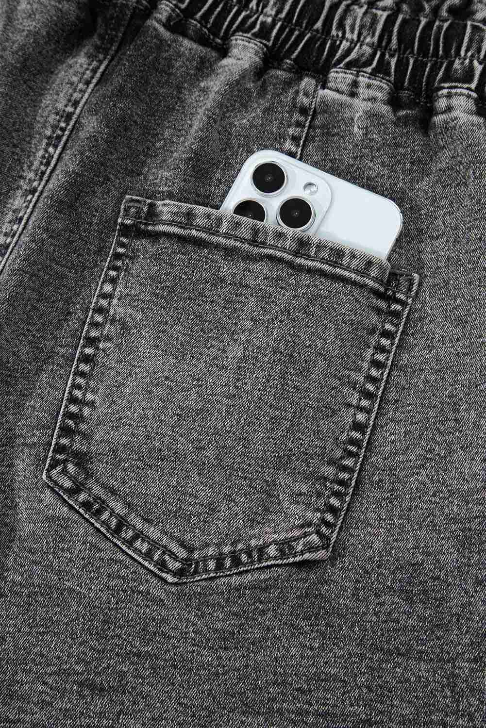 Short en jean gris foncé : poche avant avec couture, téléphone blanc glissé dans la poche