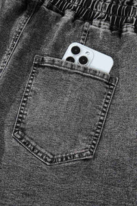 Short en jean gris foncé : poche avant avec couture, téléphone blanc glissé dans la poche