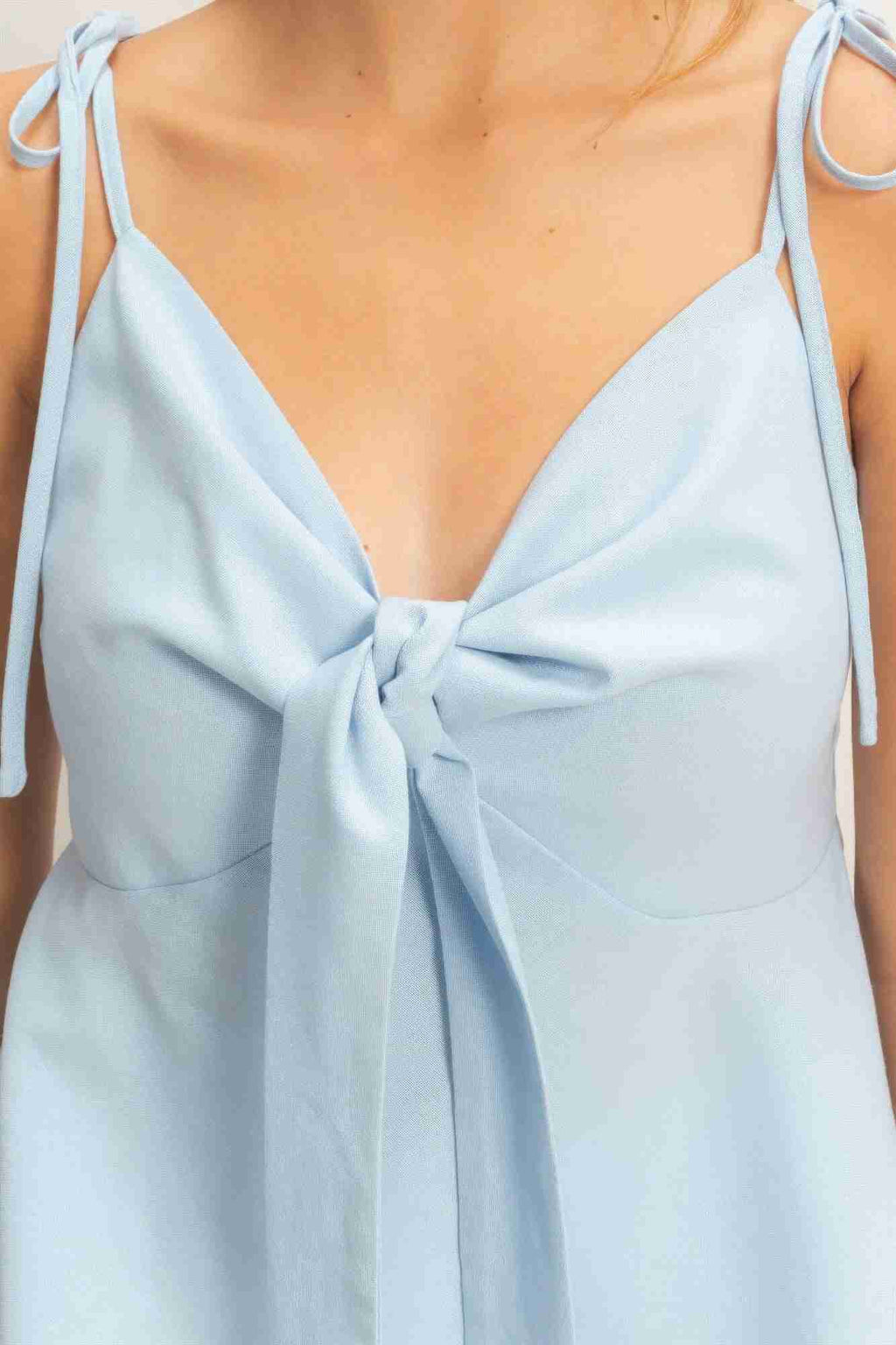 Top bleu ciel à fines bretelles nouées, nœud devant au niveau du buste
